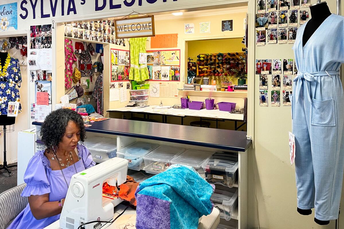 A woman sits at a sewing machine under the words Sylvia's Design Studio.