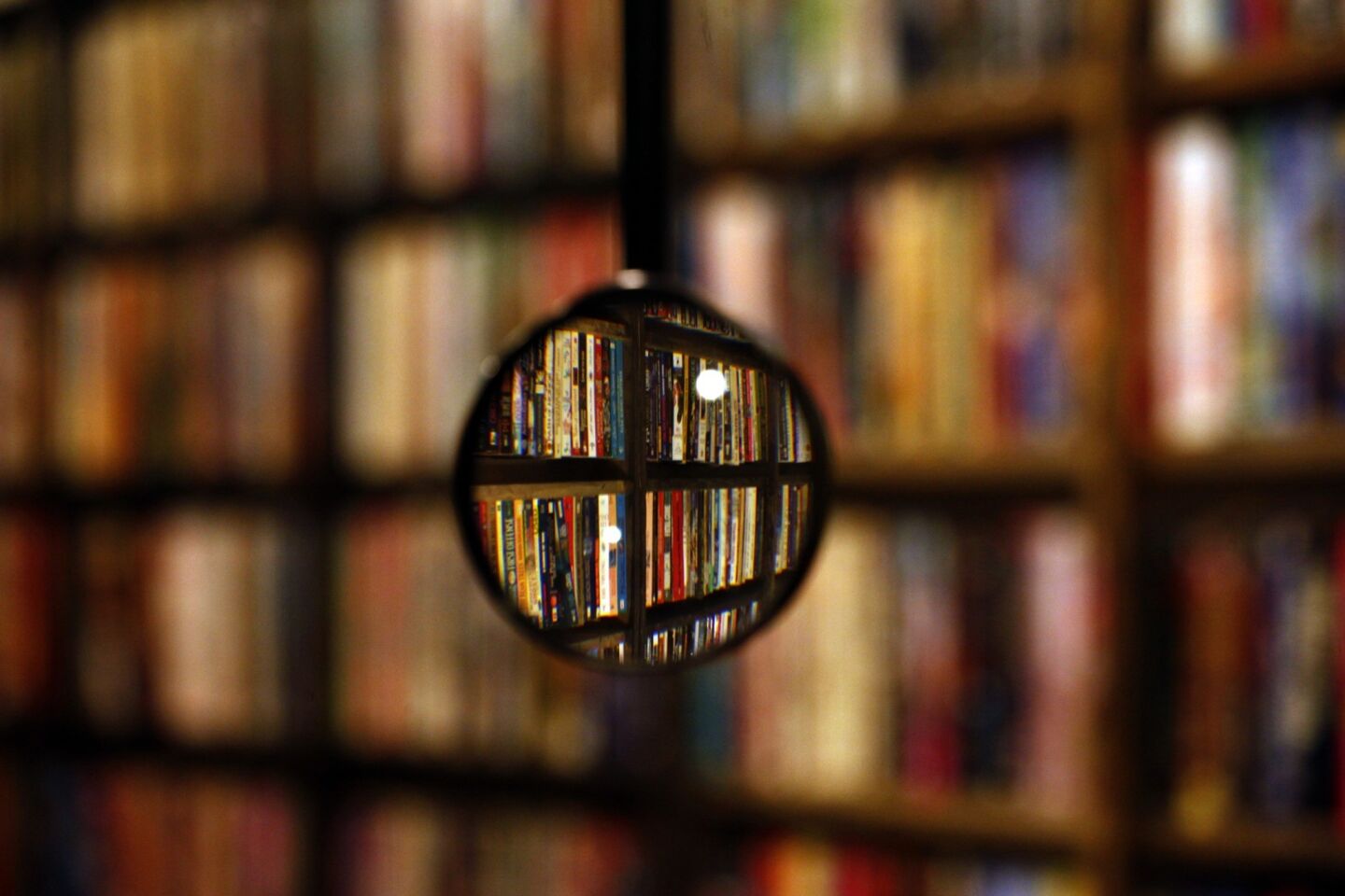 A magnifying glass, hanging from the ceiling, brings books into a sharper focus.
