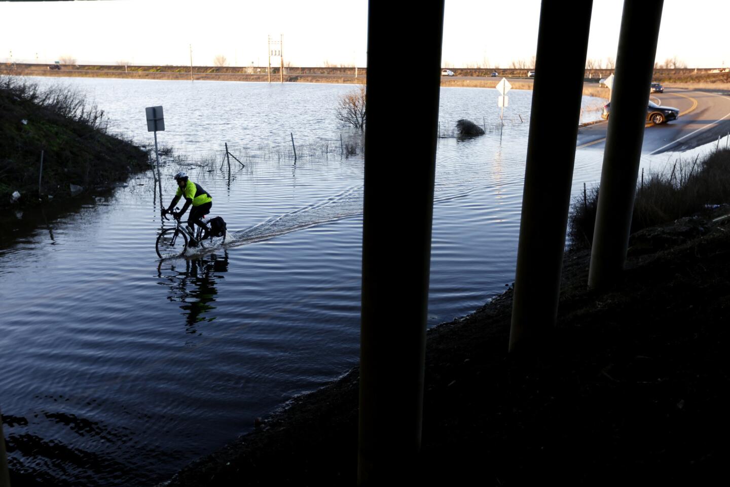 A bicyclist makes his way through East Chiles Road, which remains flooded at the underpass to Interstate 80 in the Yolo Bypass area, west of Sacramento.