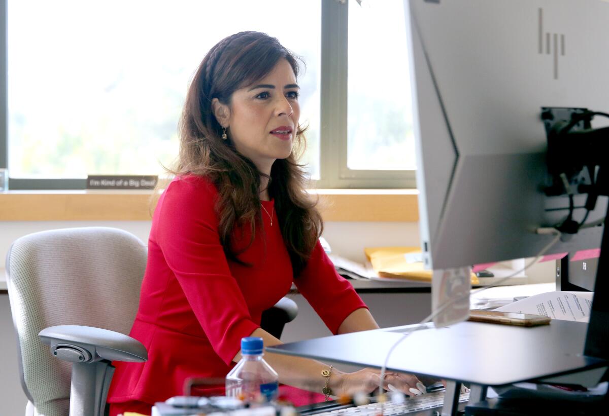 A woman sits at a computer workstation.