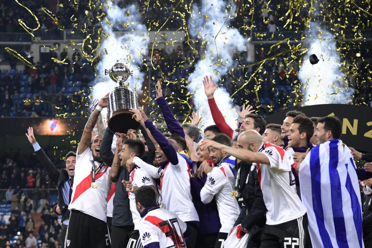Players of River Plate celebrate with the trophy after winning the second leg match of the all-Argentine Copa Libertadores final against Boca Juniors, at the Santiago Bernabeu stadium in Madrid, on December 9, 2018.