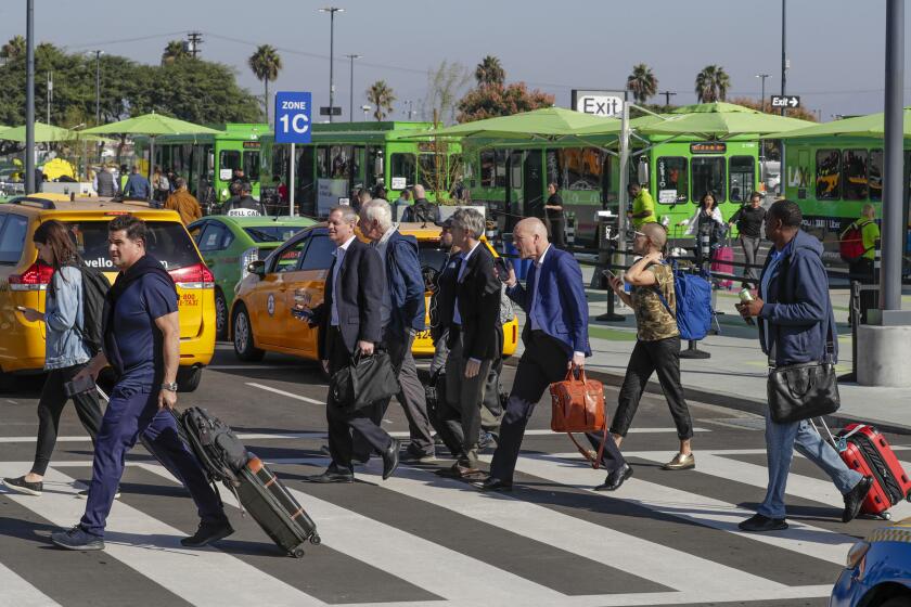 LOS ANGELES, CA - NOVEMBER 05, 2019 -- Arriving passengers holding mobile phones at new pickup lot “LAXit” at Los Angeles International Airport on Tuesday November 05, 2019. Following days of complaints over long lines and long waits, Los Angeles International Airport has decided to significantly expand the new pickup lot for Uber, Lyft and taxis. (Irfan Khan / Los Angeles Times)
