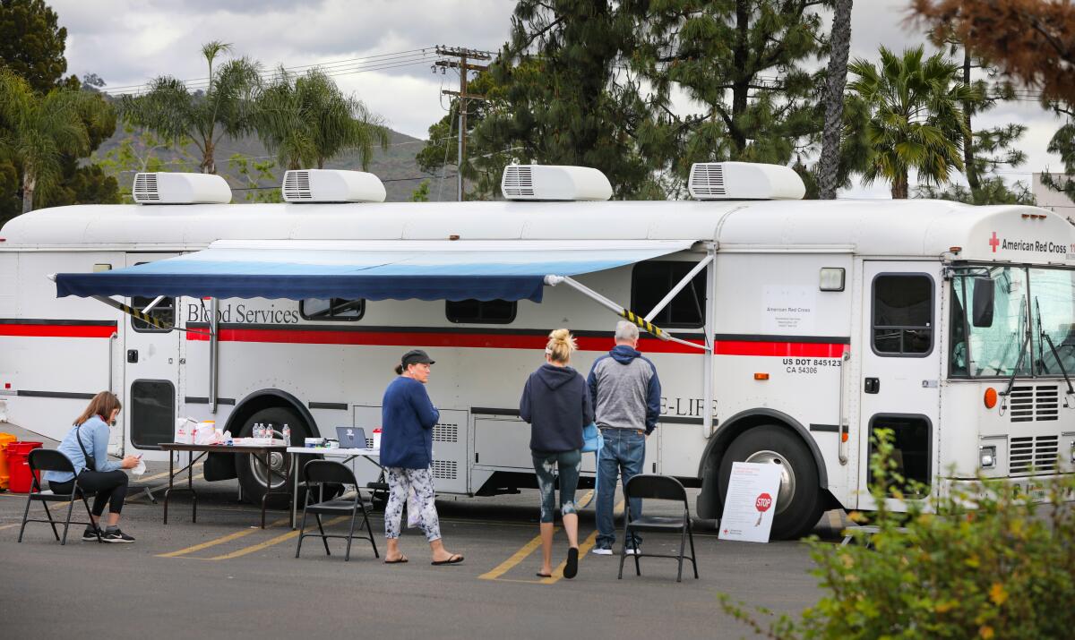 Donors wait outside a van to give blood.