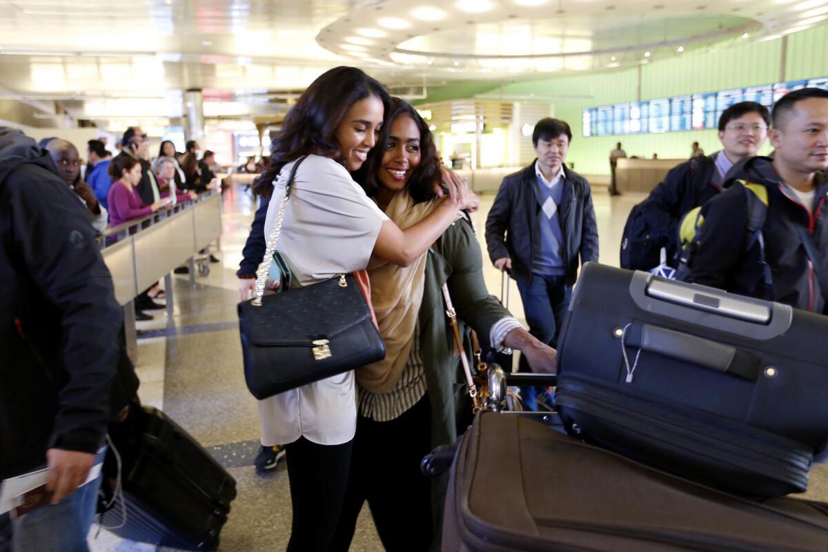 Abeer Abdelrahman, left, hugs her sister Areej Ali at the Tom Bradley International Terminal at LAX on Monday after Ali, who has a green card, was able to come through the arrivals area with the help of an attorney after being detained and questioned.