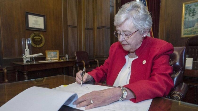 Alabama Gov. Kay Ivey signs a bill that virtually outlaws abortion in the state on Wednesday in Montgomery, Ala.
