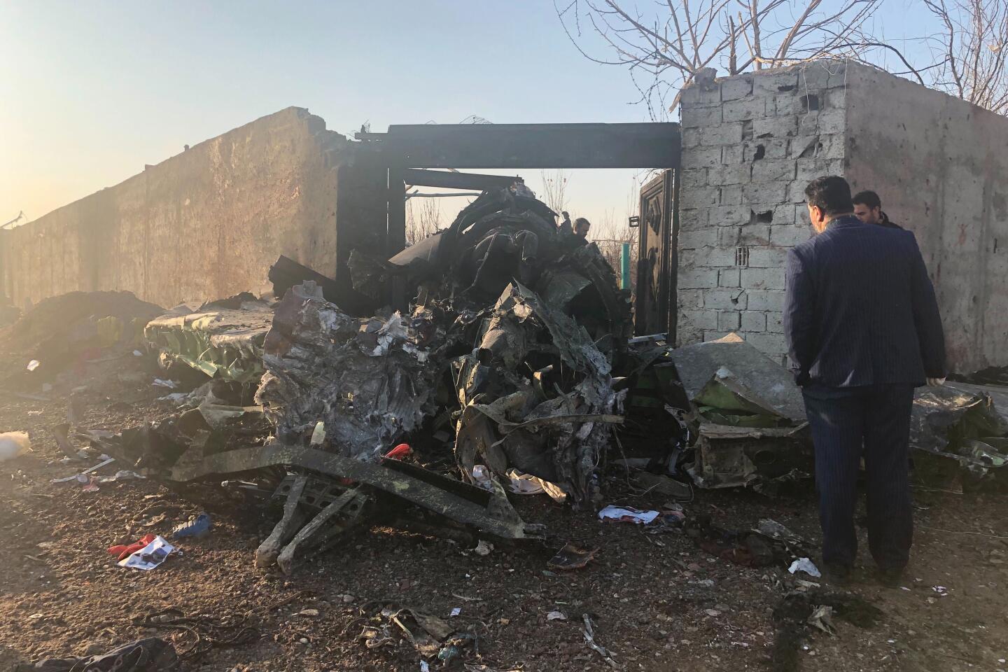 People observe some of the debris on Wednesday. The plane had taken off from Imam Khomeini International Airport in the Iranian capital when a fire struck one of its engines.