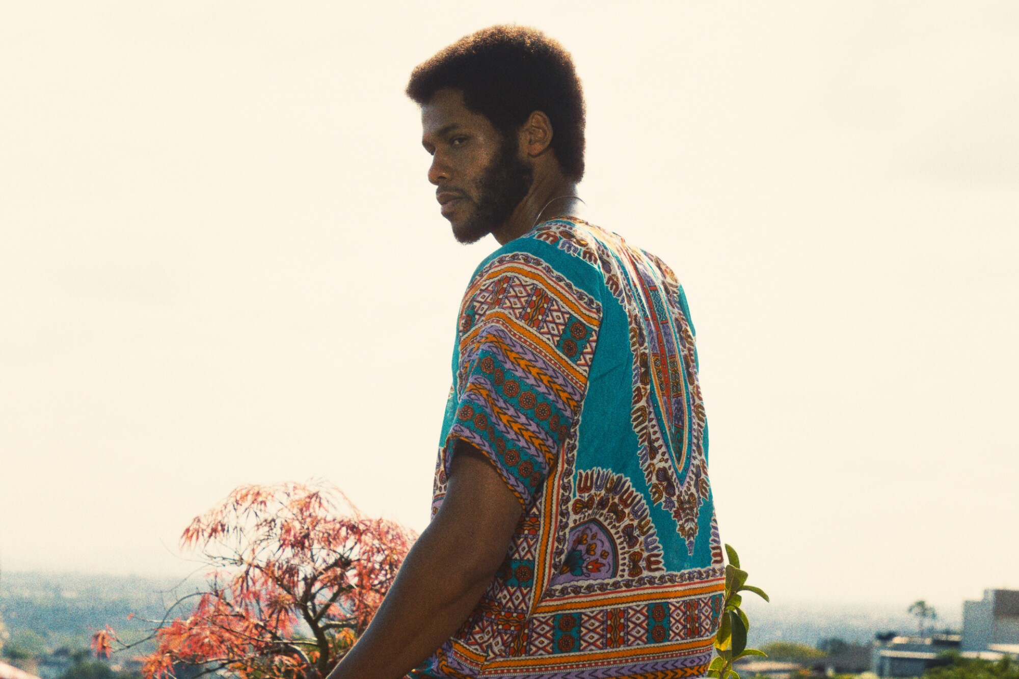 Um homem de camisa colorida, sentado ao ar livre com vista para Los Angeles.