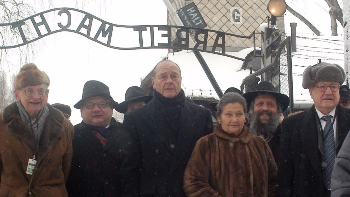 French President Jacques Chirac, third from left, Simone Veil, third from right, and Wladyslaw Bartoszewski, left, both former Auschwitz inmates, in front of the gate that carries the infamous "Arbeit Macht Frei" inscription, Jan. 27, 2005.