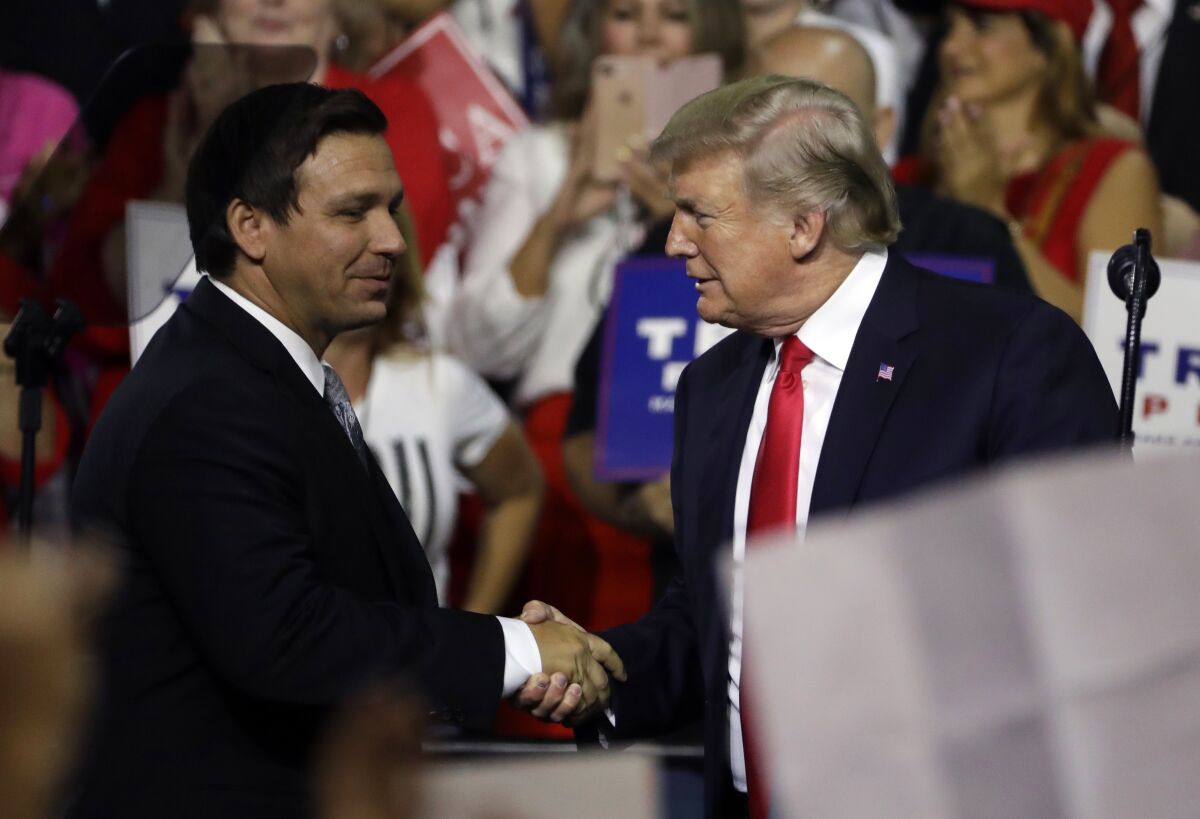 President Donald Trump, right, shakes hands with Florida Republican gubernatorial candidate Ron DeSantis during a rally Tuesday, July 31, 2018, in Tampa, Fla. (AP Photo/Chris O'Meara)