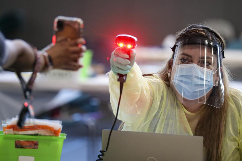 RANCHO CUCAMONGA, CA - AUGUST 20: Sylvia Carpio, a LVN, right, scans a clients QR code information at a Community COVID-19 testing site held by San Bernardino County Department of Public Health at Rancho Sports Center on Thursday, Aug. 20, 2020 in Rancho Cucamonga, CA. (Irfan Khan / Los Angeles Times)