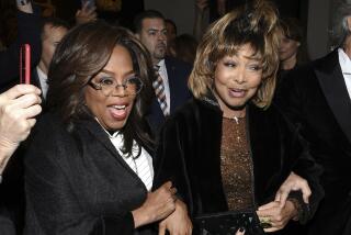 Oprah Winfrey and tina Turner smile while standing together at a theater