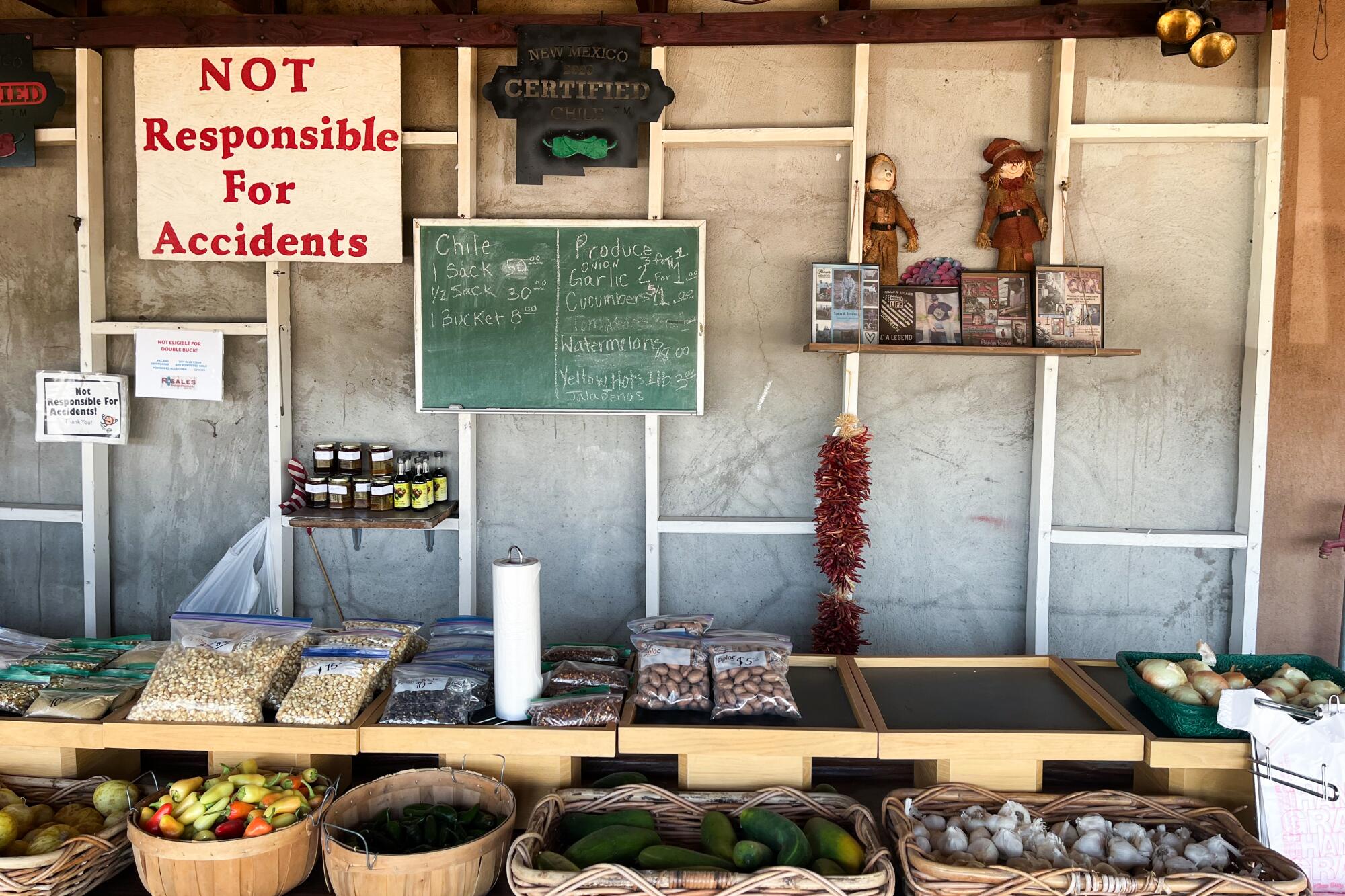 A produce stand with baskets of chiles, and a sign that reads, Not Responsible for Accidents