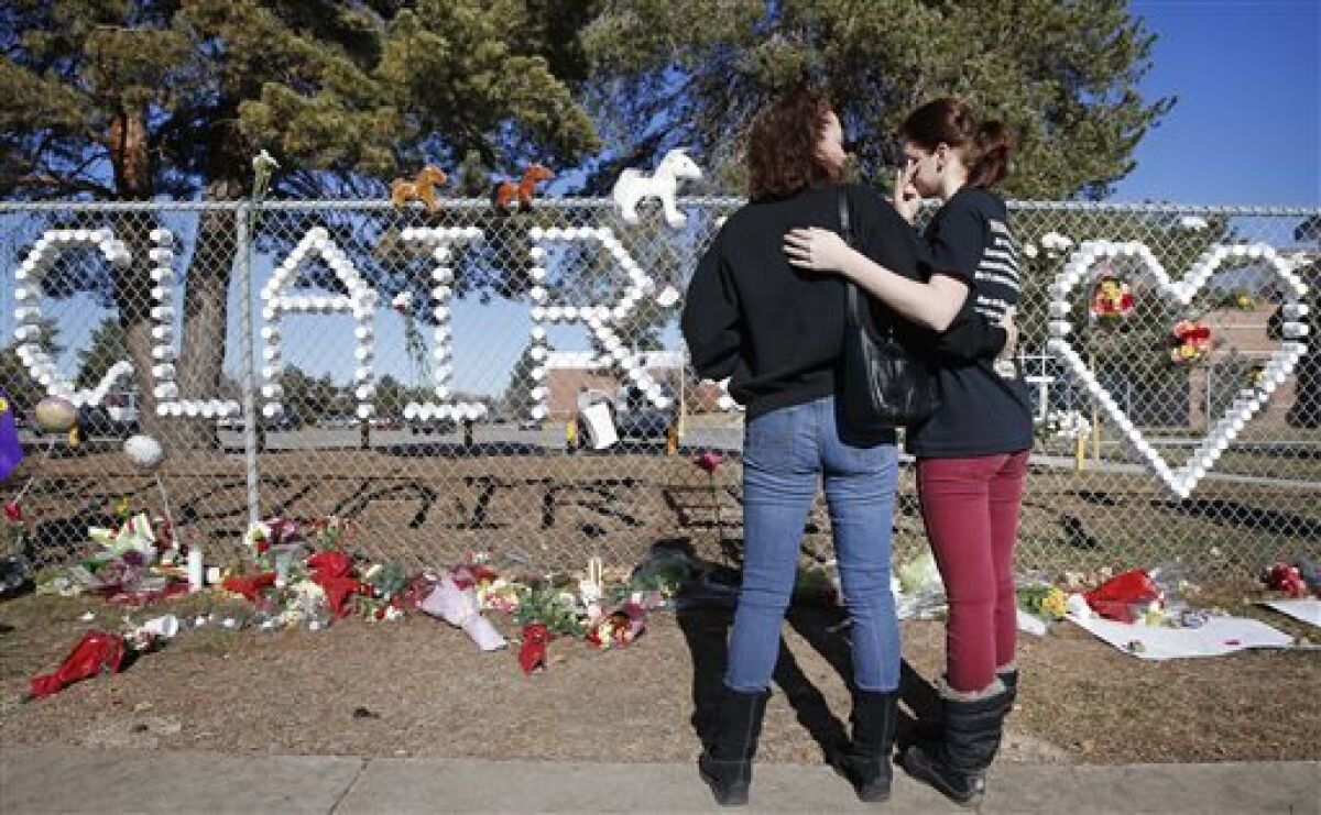 Arapahoe High School junior Emily Evans, right, and her mother, Cristina, hug while visiting a tribute bearing the name of wounded student Claire Davis, 17, who was shot by a classmate. Claire is in a coma and in critical condition.