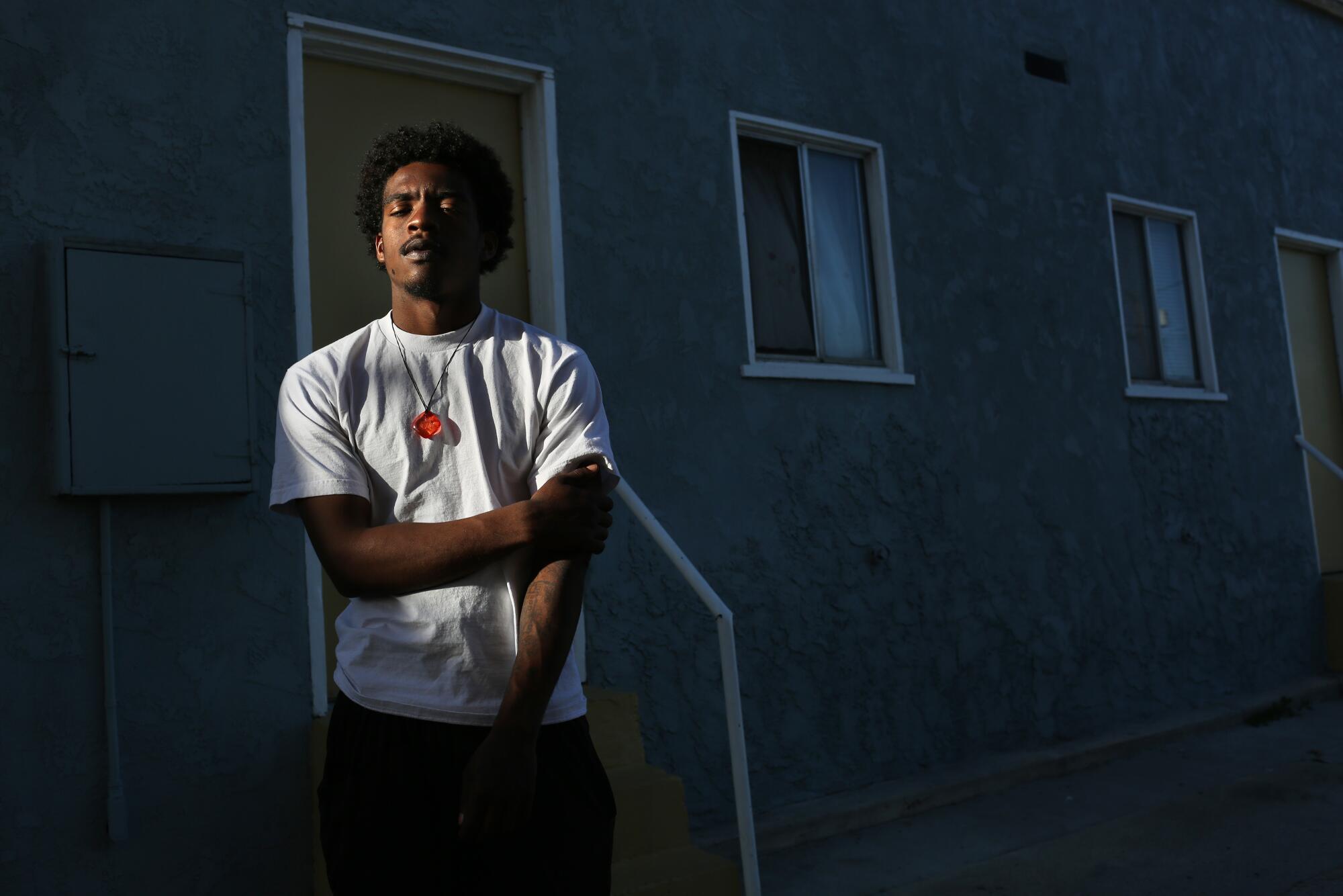 Ja'quest Jones, 19, stands for a portrait across the street from the apartment where he sometimes stays with his mom