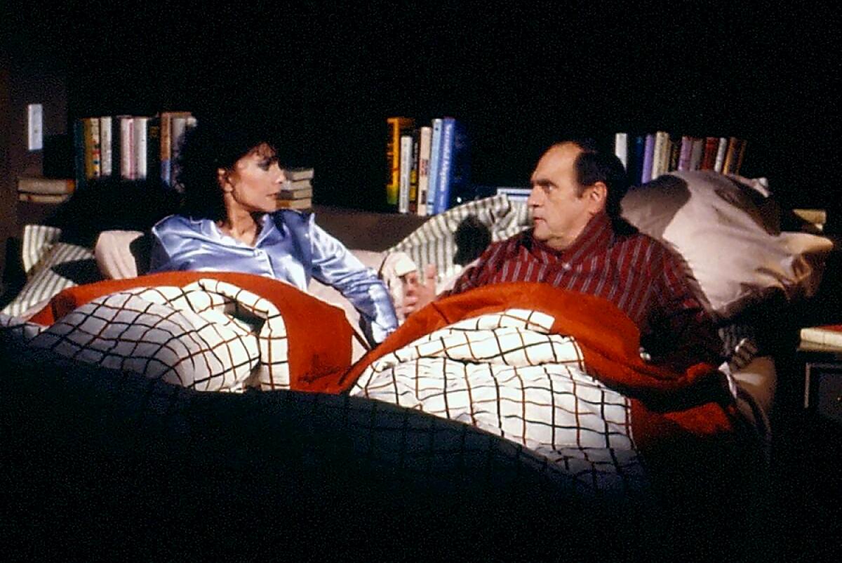 Suzanne Pleshette and Bob Newhart lie in bed together in a scene from a sitcom