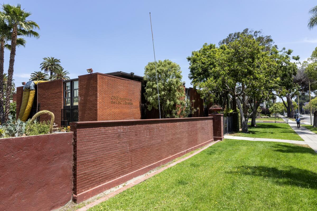 A brick building fronted by a brick fence and a swath of green lawn.