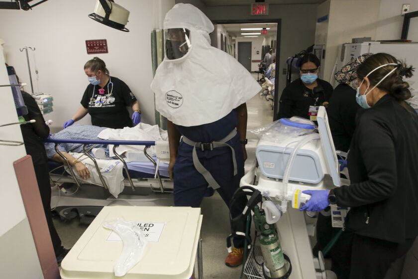 Victorville, CA - December 17: Emergency department medical director Dr. Leroy Pascal, in white mask, and emergency room nurses scramble to attend to a COVID-19 patient at Desert Valley Hospital on Thursday, Dec. 17, 2020 in Victorville, CA. (Irfan Khan / Los Angeles Times)