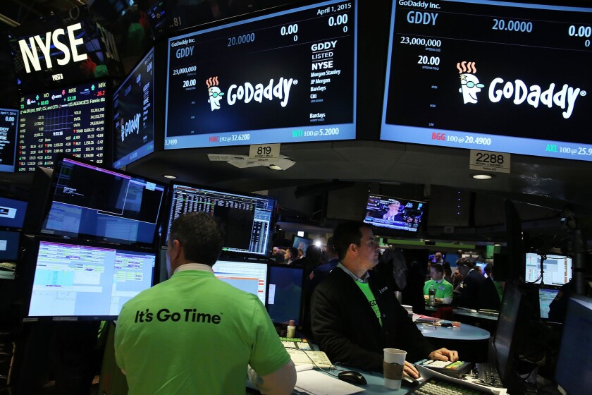 Traders work on the floor of the New York Stock Exchange as the website hosting service GoDaddy makes its public trading debut on April 1.