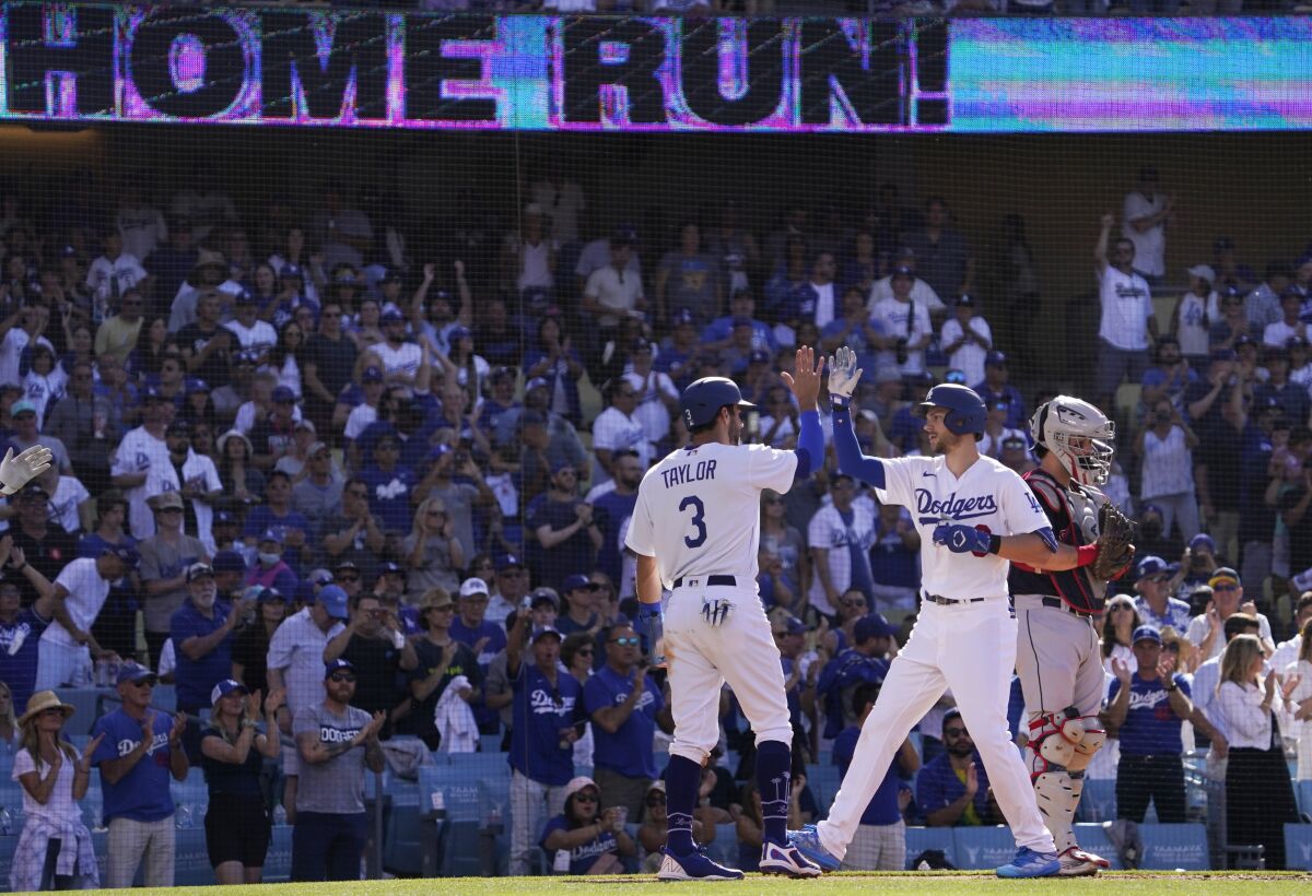 Los Angeles Dodgers' Trea Turner, center, is congratulated by Chris Taylor, left, after hitting a two-run home run as Cleveland Guardians catcher Austin Hedges stands at the plate during the second inning of a baseball game Saturday, June 18, 2022, in Los Angeles. (AP Photo/Mark J. Terrill)