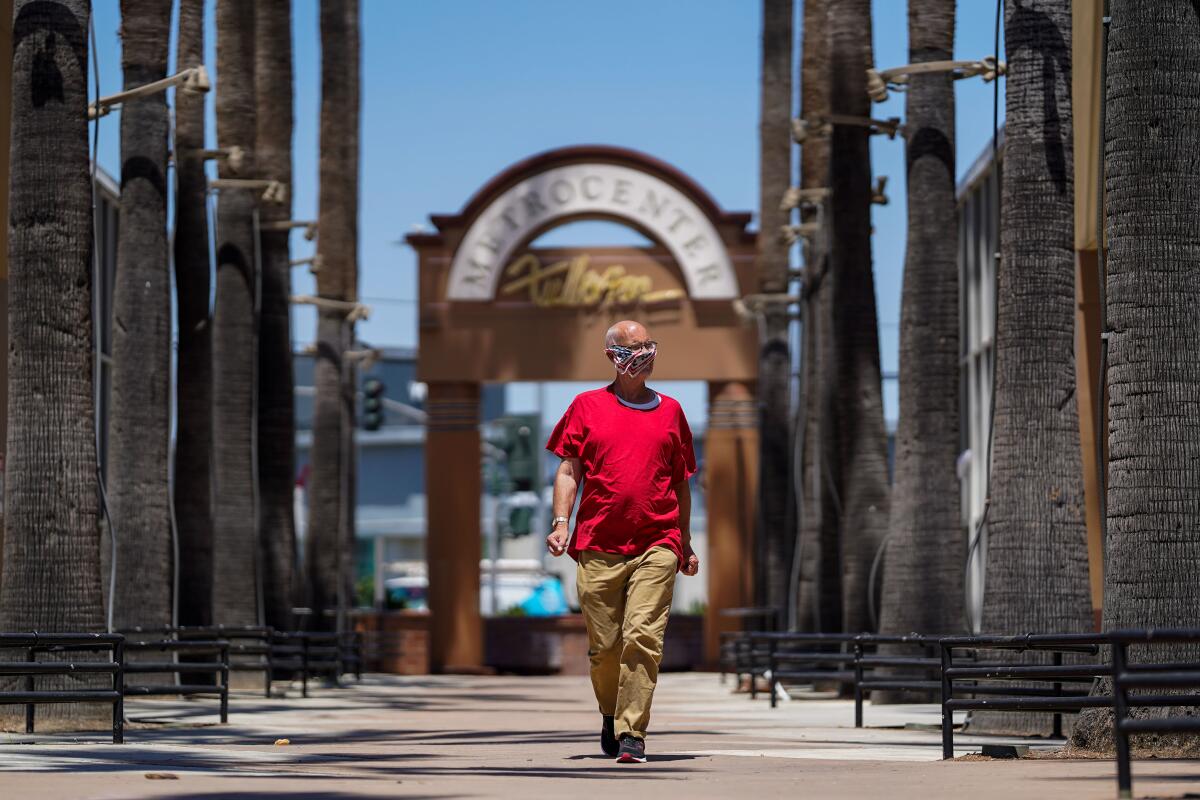 A man in a mask walks along Harbor Boulevard in downtown Fullerton last week.