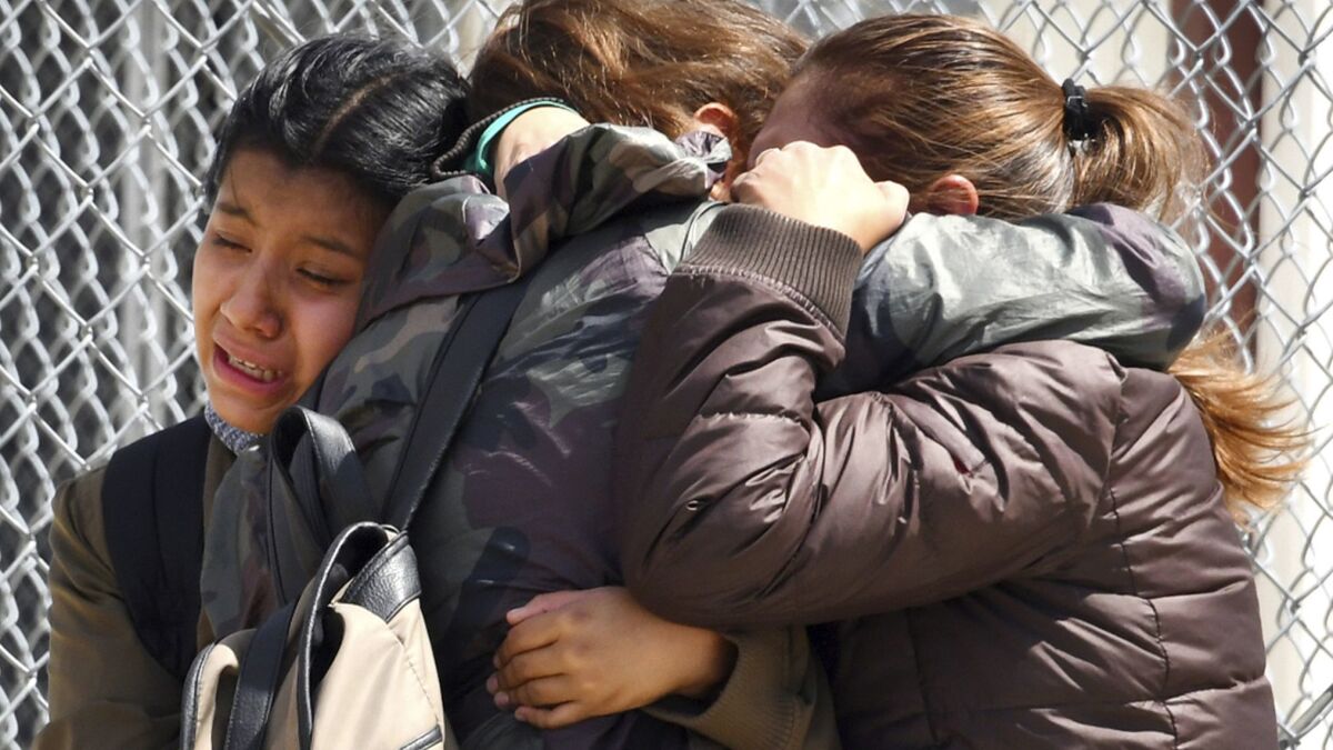 Student Melany Aquino, center, is embraced by her younger sister Halie, 11, left, and mother Victoria after a gunman fired a rifle at Highland High School in Palmdale.