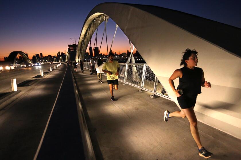 LOS ANGELES, CA - AUGUST 2, 2023 - As dusk settles over Los Angeles members of The Boyle Heights Bridge Runners make their way across the Sixth Street Viaduct in Los Angeles on August 2, 2023. The team starts at the Mariachi Plaza, makes their way down S. Boyle Avenue, halfway across the Sixth Street Viaduct and return to Mariachi Plaza. The Boyle Heights Bridge Runners is a community based running group that was founded in 2013. (Genaro Molina / Los Angeles Times)