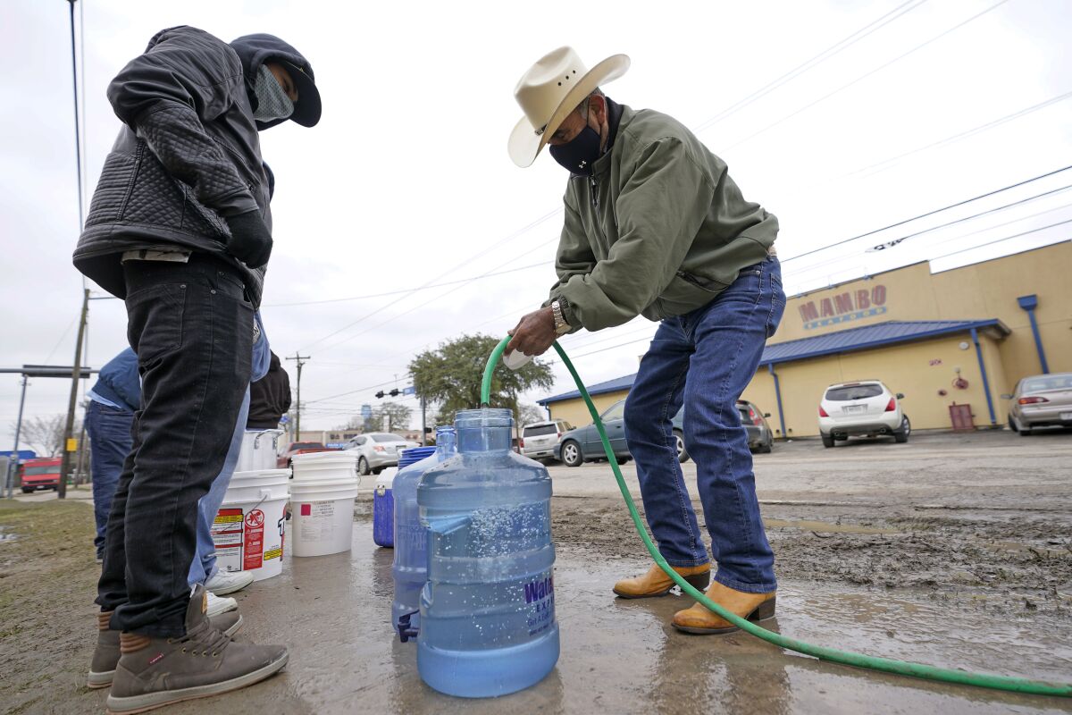People fill up water jugs at a public park