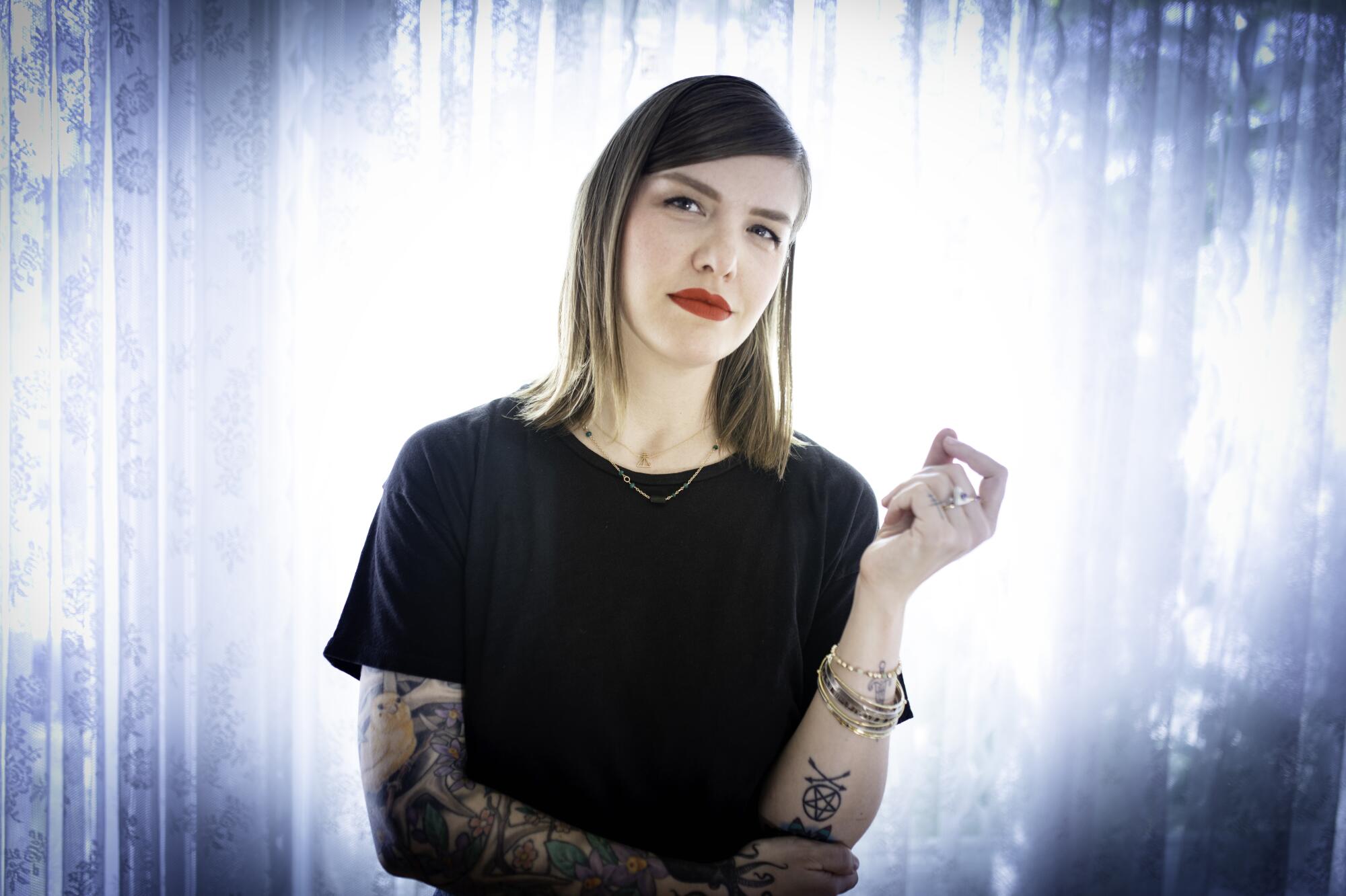 Melinda Lee Holm wears a black T-shirt and displays one heavily tattooed arm.