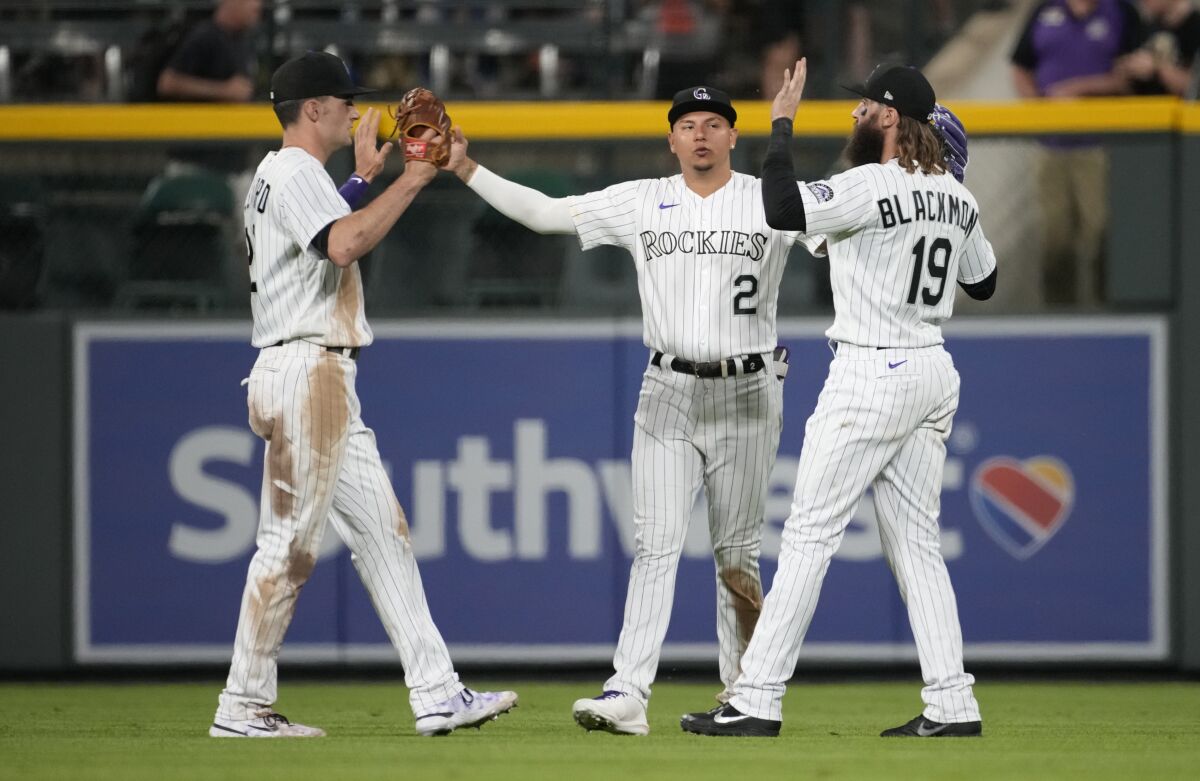 Colorado Rockies left fielder Sam Hilliard, center fielder Yonathan Daza and right fielder Charlie Blackmon, from left, celebrate the team's win over the Kansas City Royals in a baseball game Saturday, May 14, 2022, in Denver. (AP Photo/David Zalubowski)