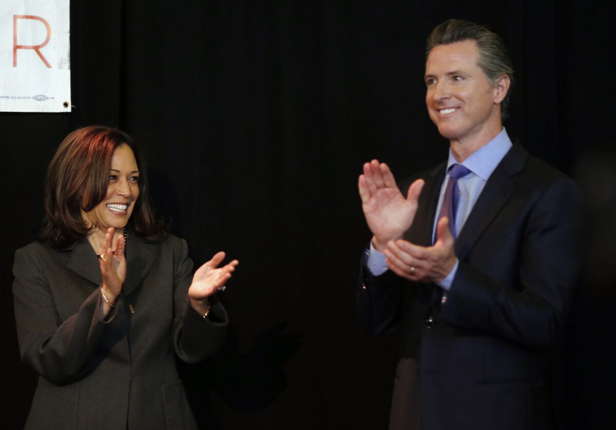 California Sen. Kamala Harris and Gov. Gavin Newsom clap on stage