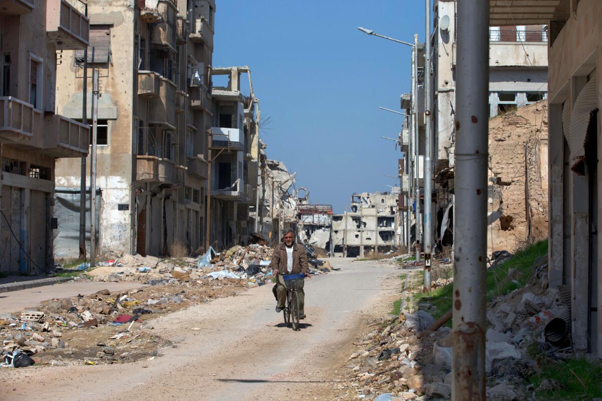 A man rides a bicycle through a devastated part of the old city of Homs, Syria, on Feb. 26.