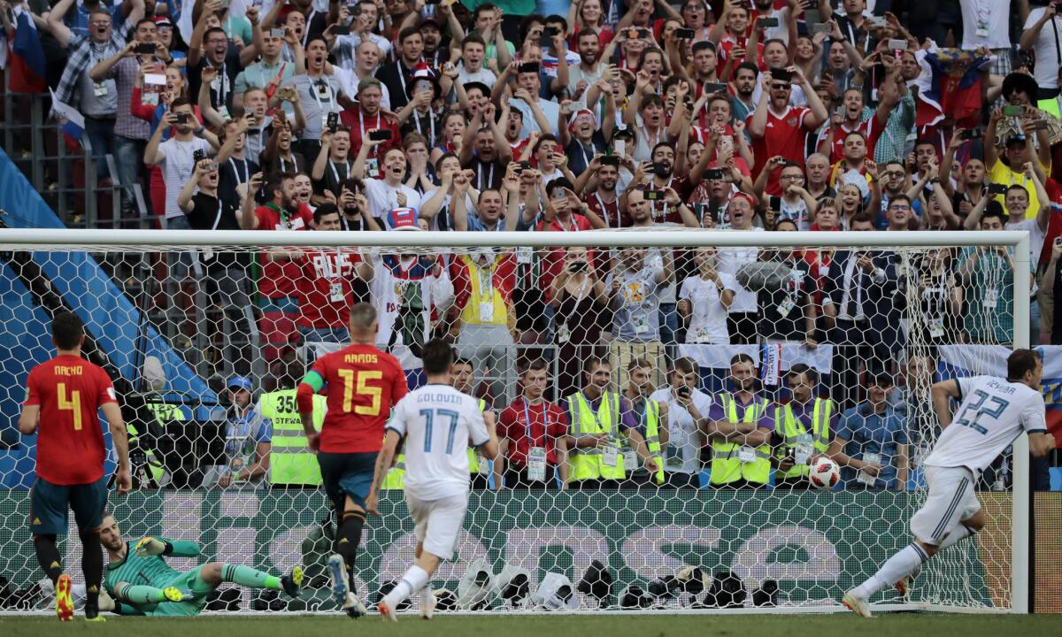 Russia's Artyom Dzyuba, right, runs to celebrate scores his side's first goal from a penalty kick past Spain goalkeeper David De Gea, 2nd left, during the round of 16 match between Spain and Russia at the 2018 soccer World Cup at the Luzhniki Stadium in Moscow, Russia, Sunday, July 1, 2018.