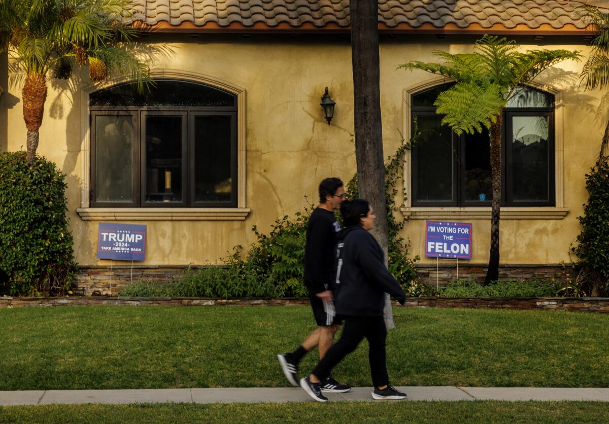 Neighbors walk past a home with signs showing support for president-elect Trump on November 18, 2024 in Downey, California.