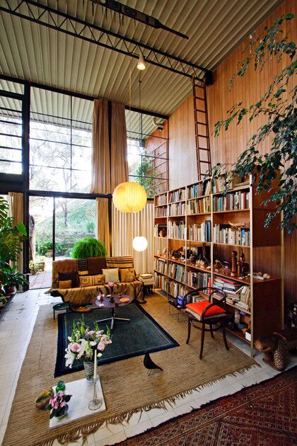 The bookcase was built at the Eames Office. The ladder reaching toward the corrugated steel ceiling allowed Charles to rearrange hanging light fixtures and string paintings face down, parallel to the floor, so if one were to look up, one would see a gallery on the ceiling.
