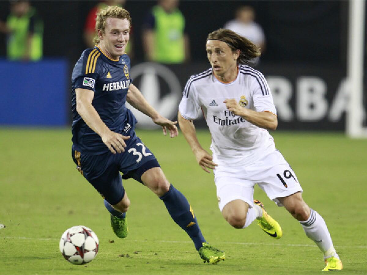 Galaxy forward Jack McBean, left, and Real Madrid midfielder Luca Modric chase a loose ball last month.