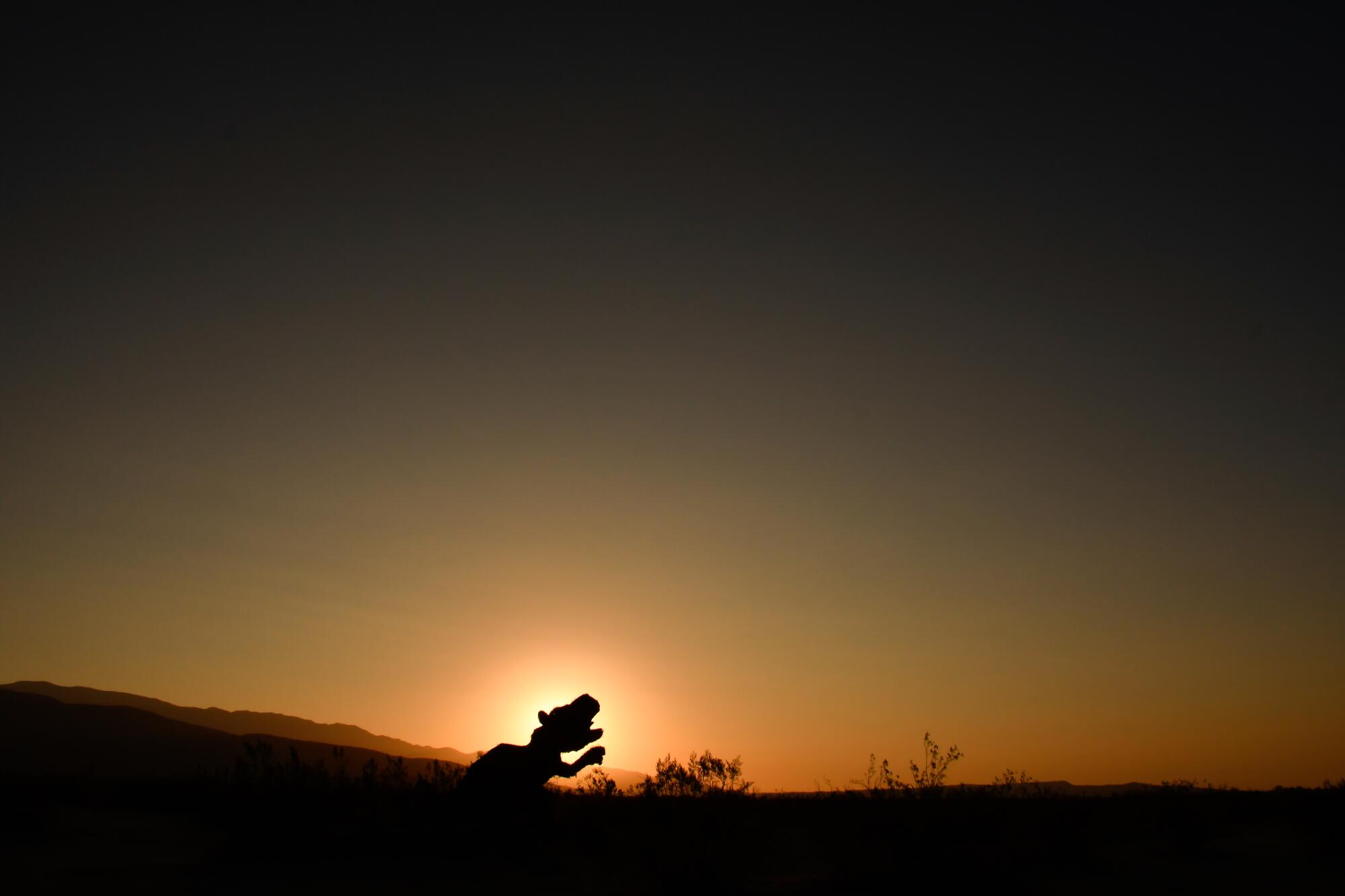 The silhouette of an animal sculpture at sunrise