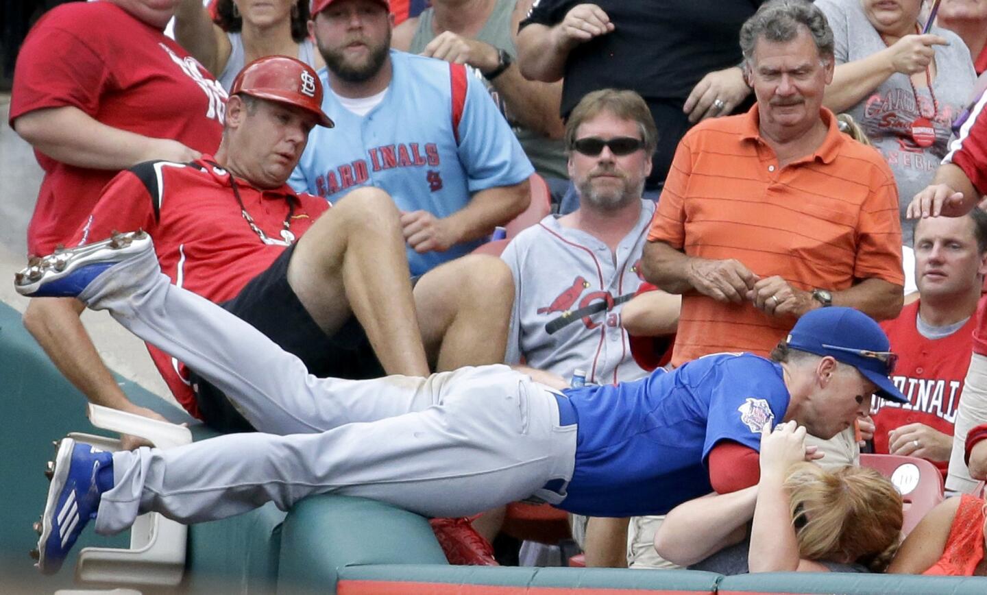 Cubs right fielder Chris Coghlan dives into the crowd to catch a foul ball hit by St. Louis Cardinals' Tommy Pham for the final out of the fifth inning.