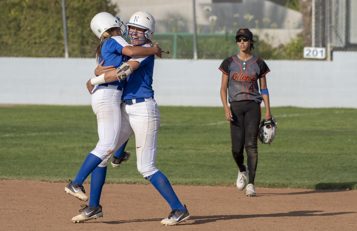 Norco's Mikayla Allee, left, jumps into the arms of Kinzie Hansen after she hit a walk off double in the ninth inning as Huntington Beach's Shelbi Ortiz walks off the field during a quarterfinal CIF Southern Section Division 1 playoff game on Thursday, May 24.