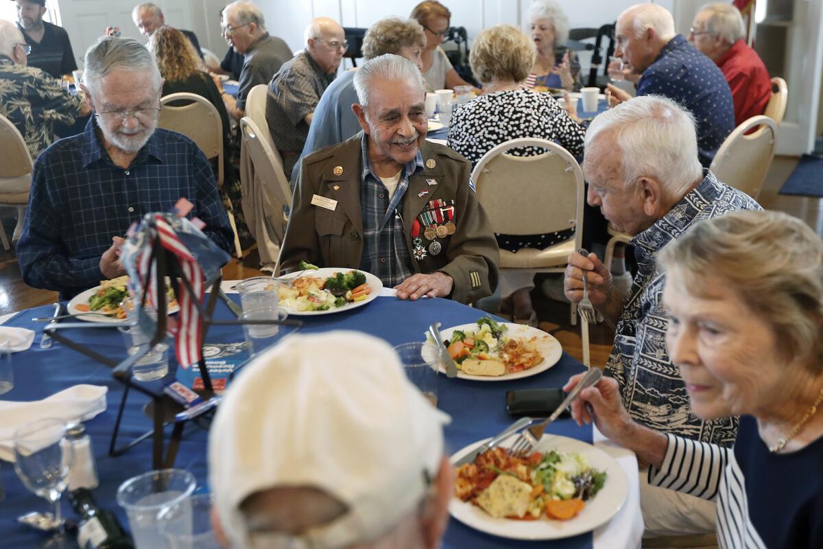 World War II veteran Cruz De Leon, 94, center, of Buena Park talks during a luncheon Thursday for WWII and Korean War veterans at American Legion Post 291 in Newport Beach. De Leon landed on Omaha Beach in France during the Battle of Normandy in 1944.