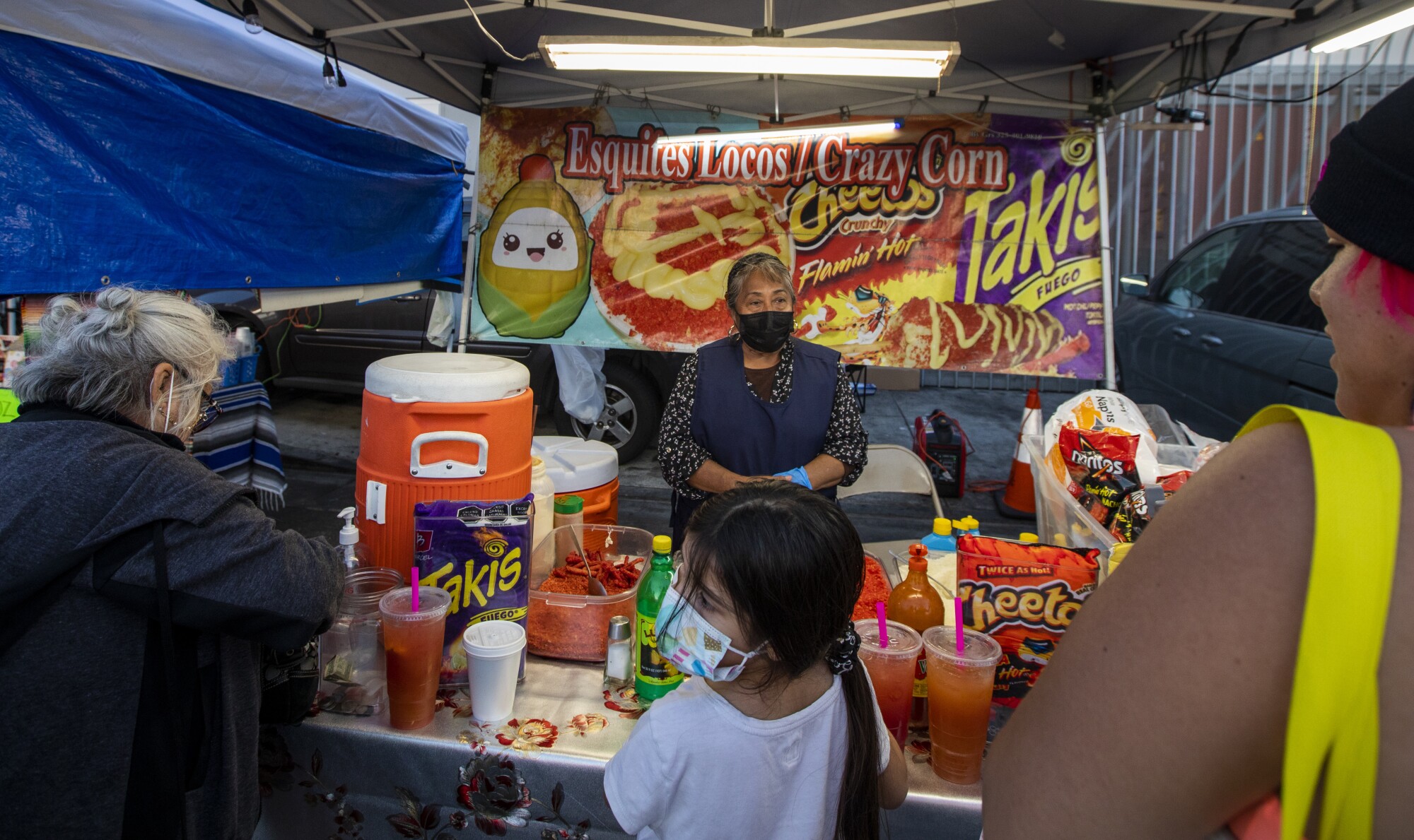 A woman greets customers at her booth in a food market.