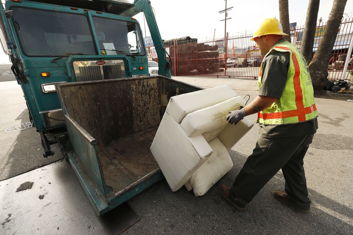 A sanitation worker loads a chair for removal