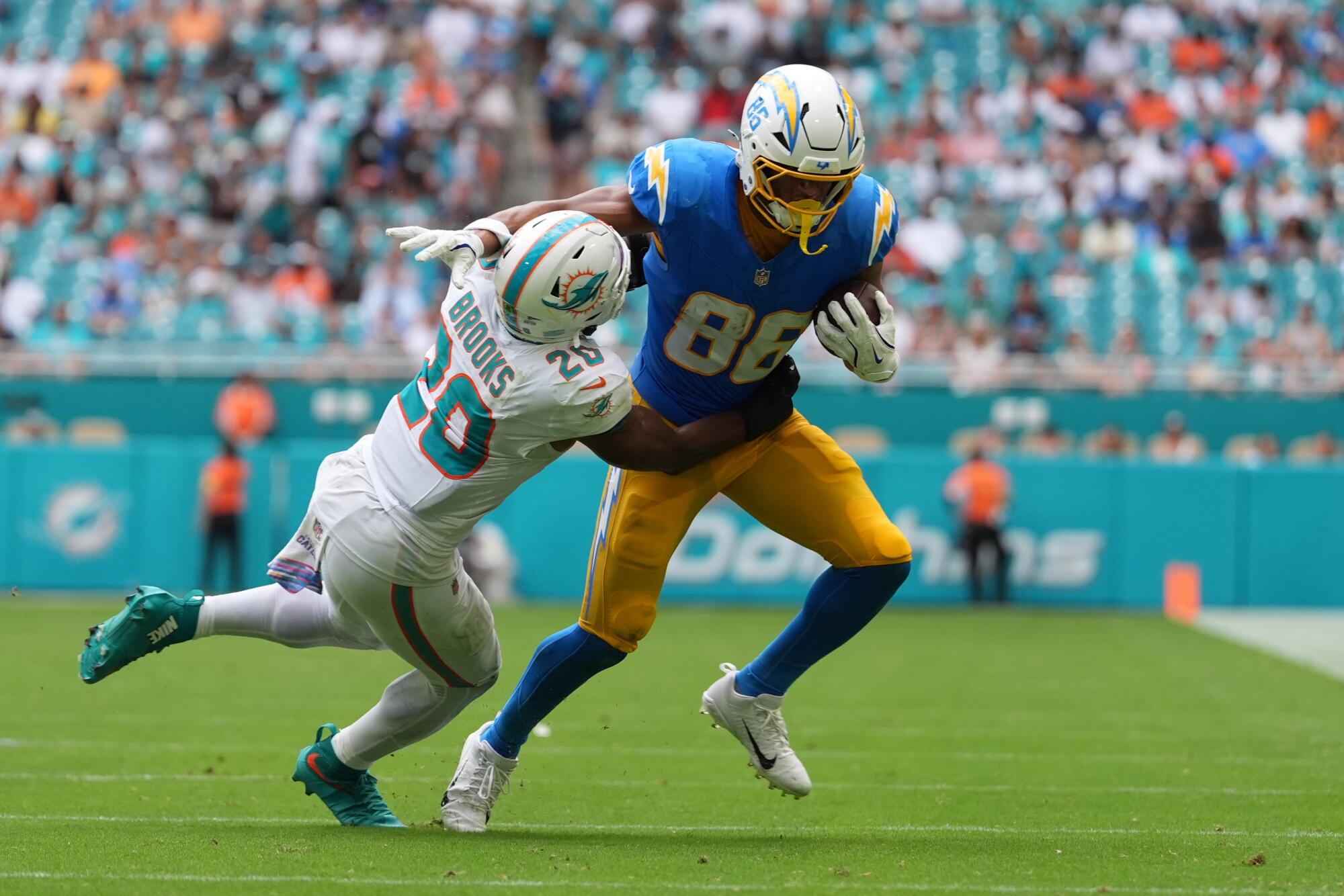 O tight end do Chargers, Oronde Gadsden II, tenta lutar contra o linebacker do Miami Dolphins, Jordyn Brooks.
