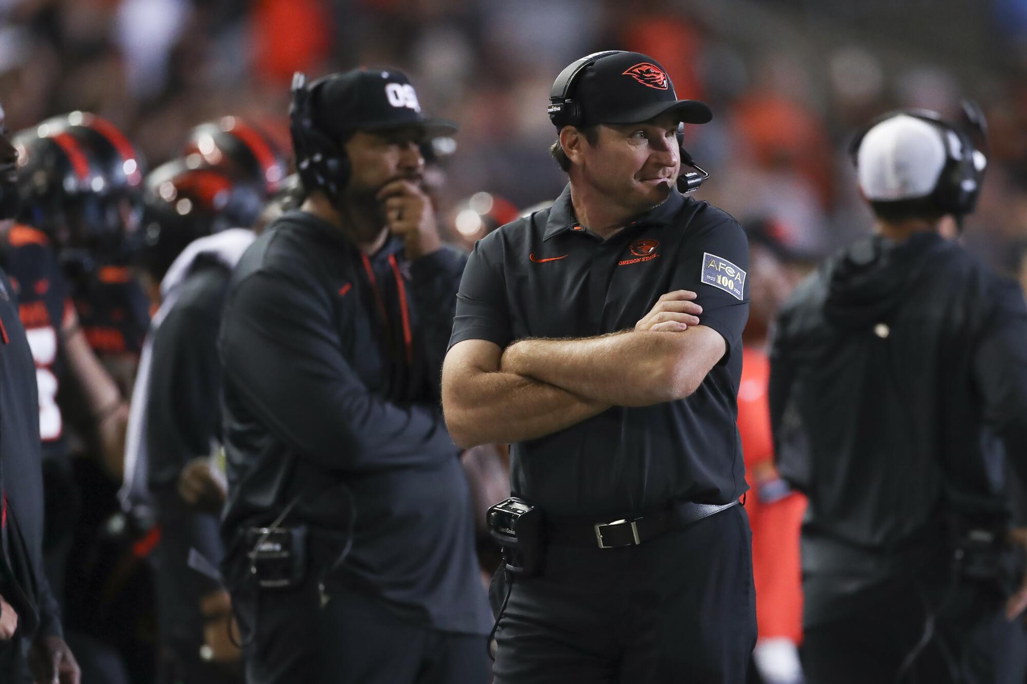 Coach Jonathan Smith stands with arms folded and watches Oregon State play.