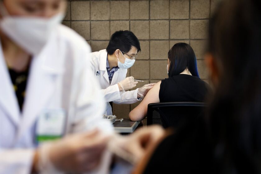 CARSON-CA-SEPTEMBER 16, 2021: Sarith Mey, center left, a pharmacist graduated intern with Rite Aid, administers a shot to CSUDH student Fritzi Bui, 29, during the final of two pop-up COVID-19 vaccination clinics hosted by Cal State Dominguez Hills and Rite Aid for CSUDH students, faculty, staff and community members on campus in Carson on Thursday, September 16, 2021. (Christina House / Los Angeles Times)