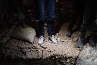 Legs of men standing around a hole.