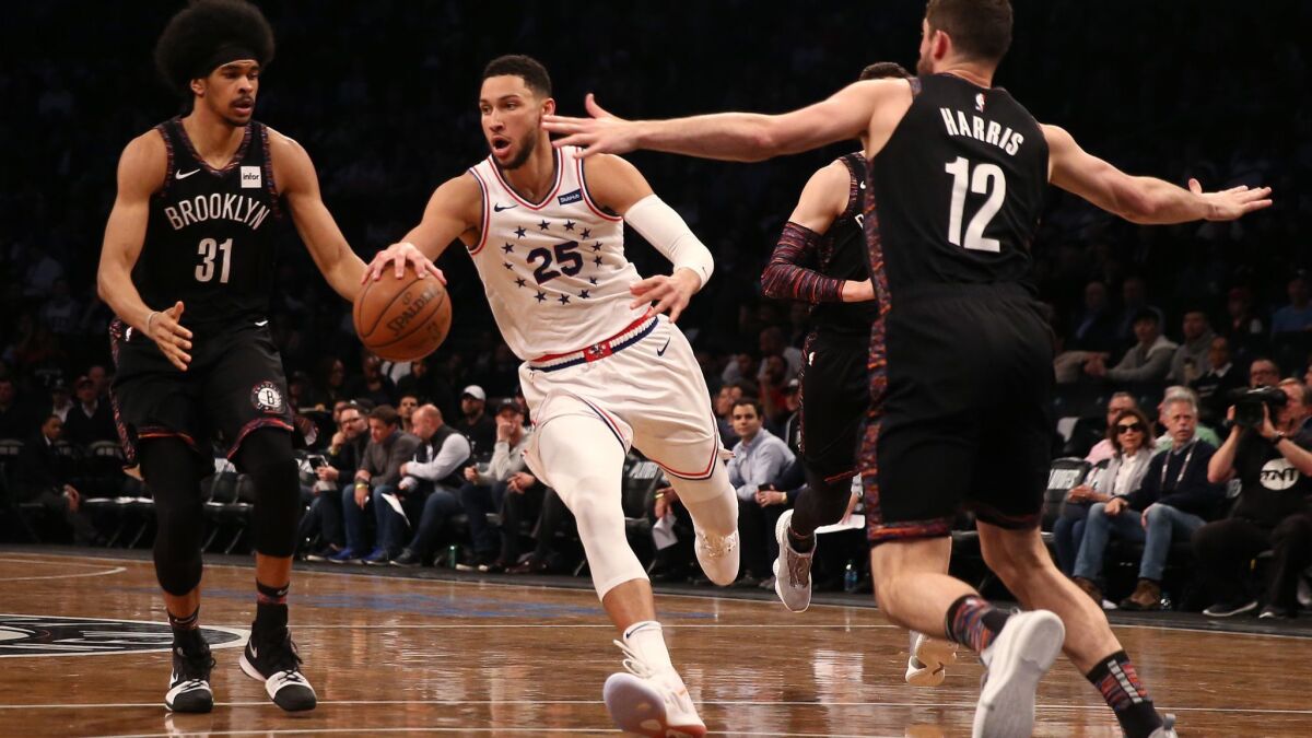 Philadelphia 76ers' Ben Simmons (25) of the Philadelphia 76ers handles the ball against Brooklyn Nets' Jarrett Allen (31) and Joe Harris (12) in the third quarter during Game 3 of round one of the NBA playoffs on Thursday.