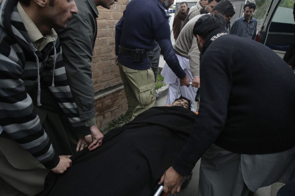 People carry the body of a police officer into an ambulance in Mardan. Pakistan, on Tuesday. Police say gunmen shot the officer while he was protecting a team of polio workers during a U.N.-backed vaccination campaign in northwestern Pakistan.
