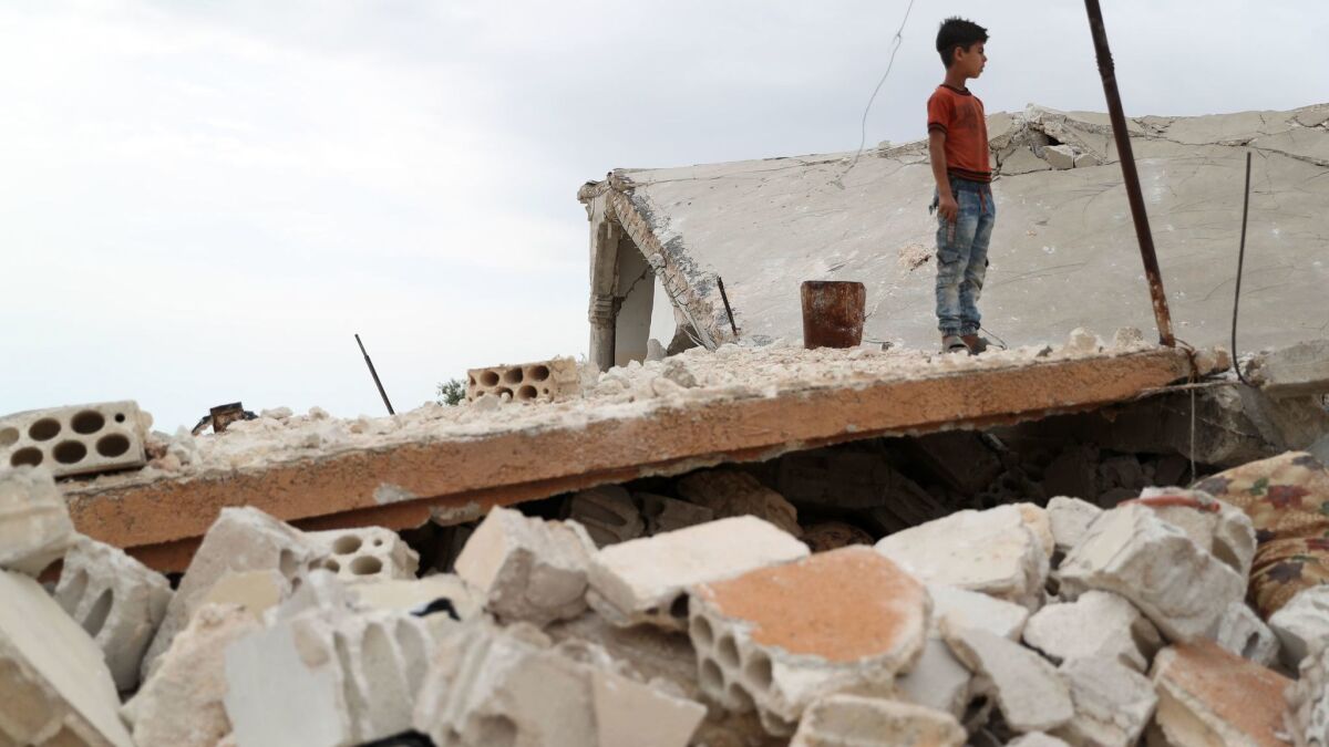 A Syrian boy stands above the rubble of a building in the village of Rabaa Jour in Idlib province, on Monday.