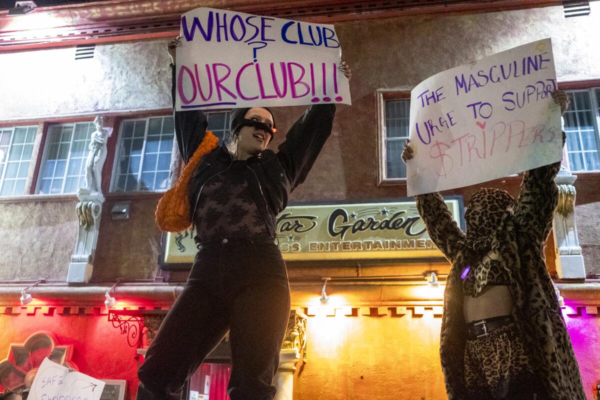 Two protesters hold signs outside of strip club Star Garden.