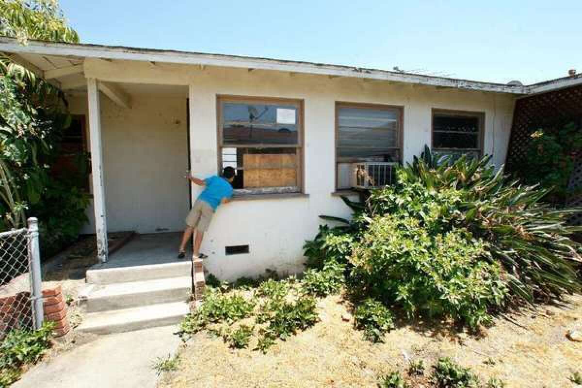A neighbor peaks into an unoccupied, foreclosed home in East Los Angeles.